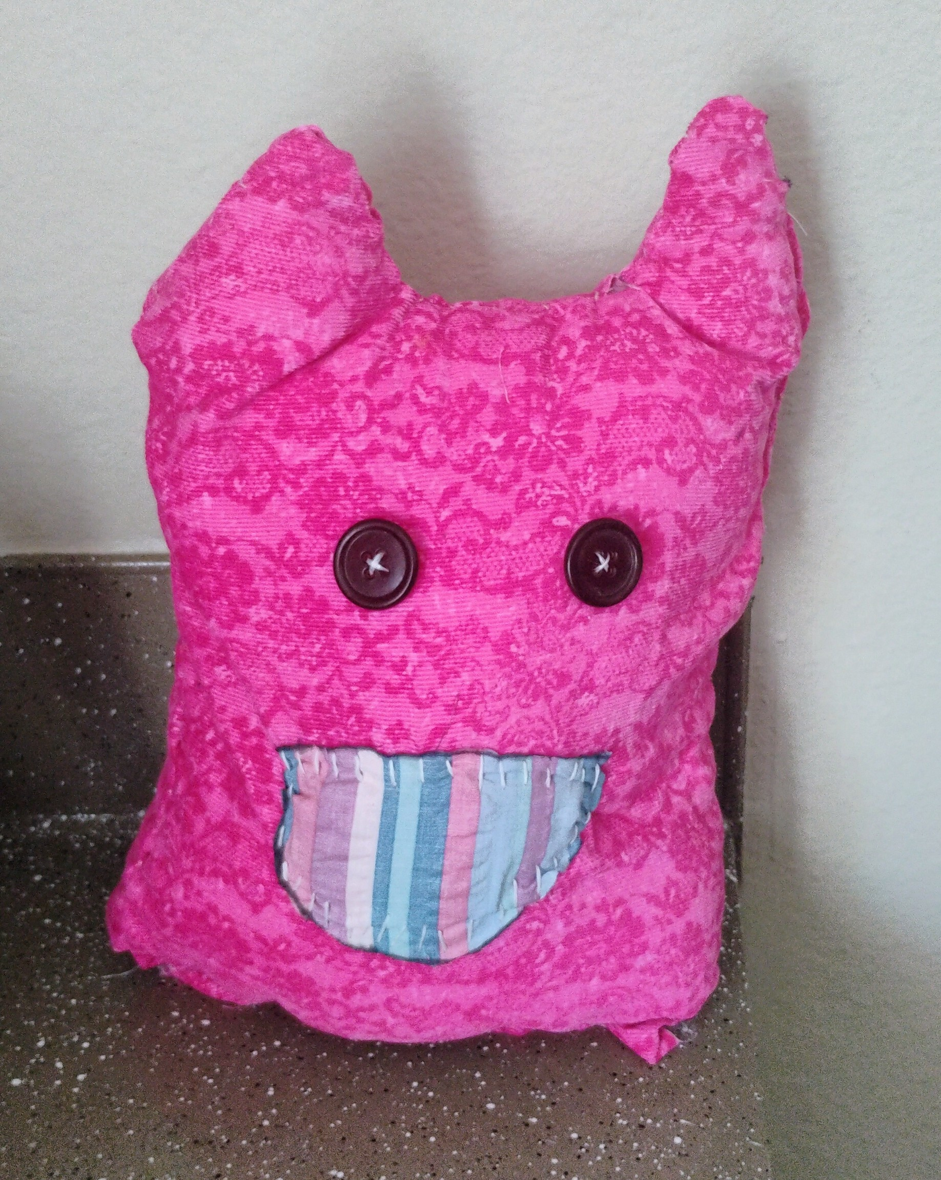 medium sized homemade hot pink floral pattern cat plush with blue striped teeth and black button eyes